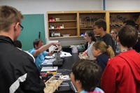 students watch test of how much weight bridges made of popsicle sticks can hold