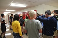 group of students taking part in scavenger hunt at high school locker