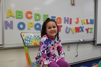 pre k student smiles next to alphabet on first day