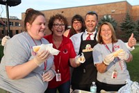 c v staff members who are helping to serve hot dogs smile for a picture