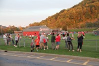 wide shot of parents and guardians watching young children play football in field near warrior stadi