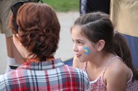 younger student gets her face painted by high school student