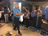 people walking through line to fill bags of food for backpack program