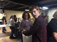 student smiles while helping to fill bag for backpack program teacher anne marie griffin puts a box 