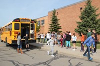 far shot of students lined up after exiting back of bus for bus drill