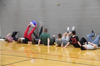 far shot of students working together to move ball with feet for teamwork challenge