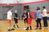 students work together to try to write a positive message using large strands of duct tape connected