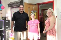 teacher smiles with parent and student at middle school open house