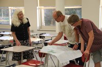 teacher talks with middle school student and parent at open house