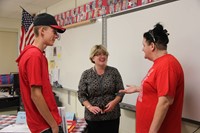 teacher talks with student and parent at middle school open house