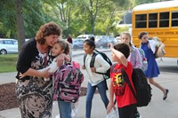 student hugs principal mary beth hammond while another student waves hello on first day of school