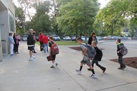 wide shot of elementary students walking towards school on first day