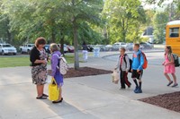 wide shot of student stopping to speak with principal mary beth hammond before entering elementary s