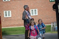 students walk towards elementary school and student gives principal jim pritchard a high five in the