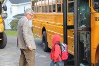 principal jim pritchard welcomes students getting off bus to elementary school