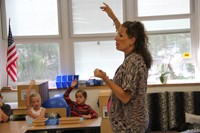 teacher asks question and students raise their hand to answer question