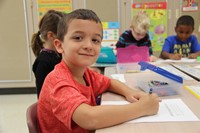 student takes a moment to smile while coloring at port dickinson elementary
