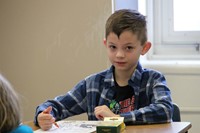 boys looks up and smiles while coloring