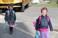 girls smile while walking towards port dickinson elementary school after getting off bus