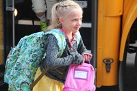 girl smiles walking toward first day of school