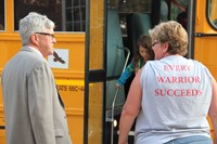 principal jim pritchard and bus monitor help students to get off bus