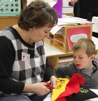 adult helping student cut hat