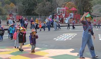 pre k students and teacher walking in halloween parade