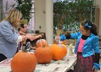 students and teacher painting pumpkins