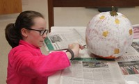 student painting pumpkin