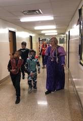 students and teacher walking down hall in costumes