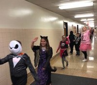 students and teacher wearing costumes walking down hallway
