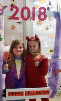 two students in costume at photo booth sign