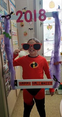 student wearing costume at photo booth sign