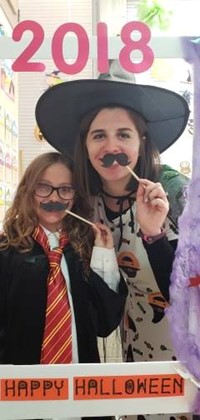 student and teacher in halloween costumes with photo booth sign