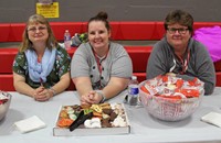 three people smiling at snack table