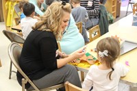 adult working with child on scarecrow hat