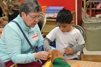 family member helping pre k student make a scarecrow hat