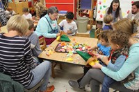 family members helping pre k students make scarecrow hats