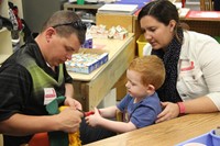 adults helping student cut scarecrow hat