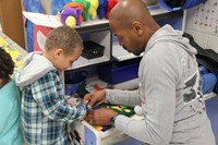 man helping student to cut a felt scarecrow hat