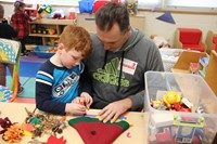 man helps boy make a scarecrow hat at pre k family day