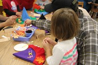 man helps girl make purple scarecrow hat