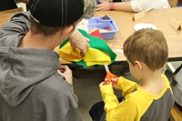 man helping boy cut scarecrow hat