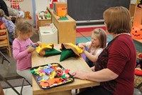 woman and two girls making scarecrow hats