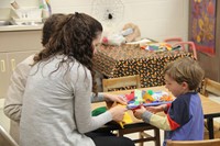 woman helping child to cut felt scarecrow hat