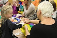 woman holds felt scarecrow hat while pre k student cuts it