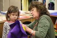 woman works with girl to make a purple scarecrow hat