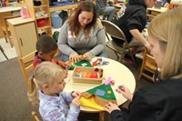 women helping children make hats at pre k family day