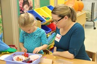 woman helping girl make a felt scarecrow hat