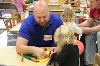 man helping child with scarecrow hat